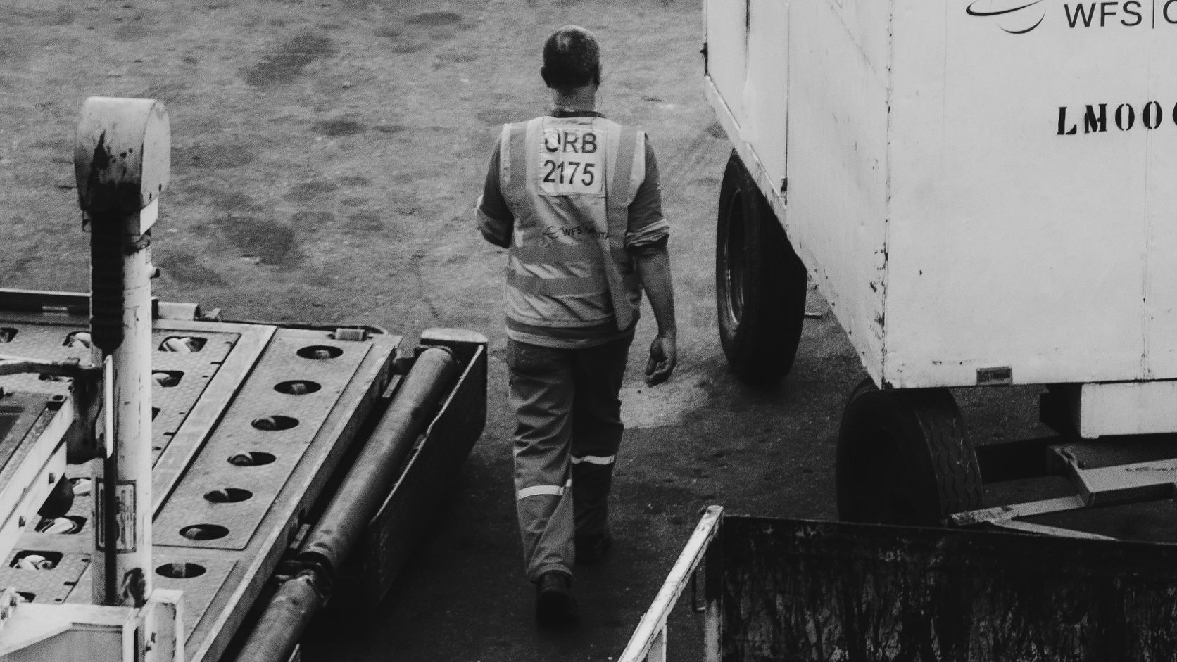 Airport ground crew member walking among cargo-handling equipment